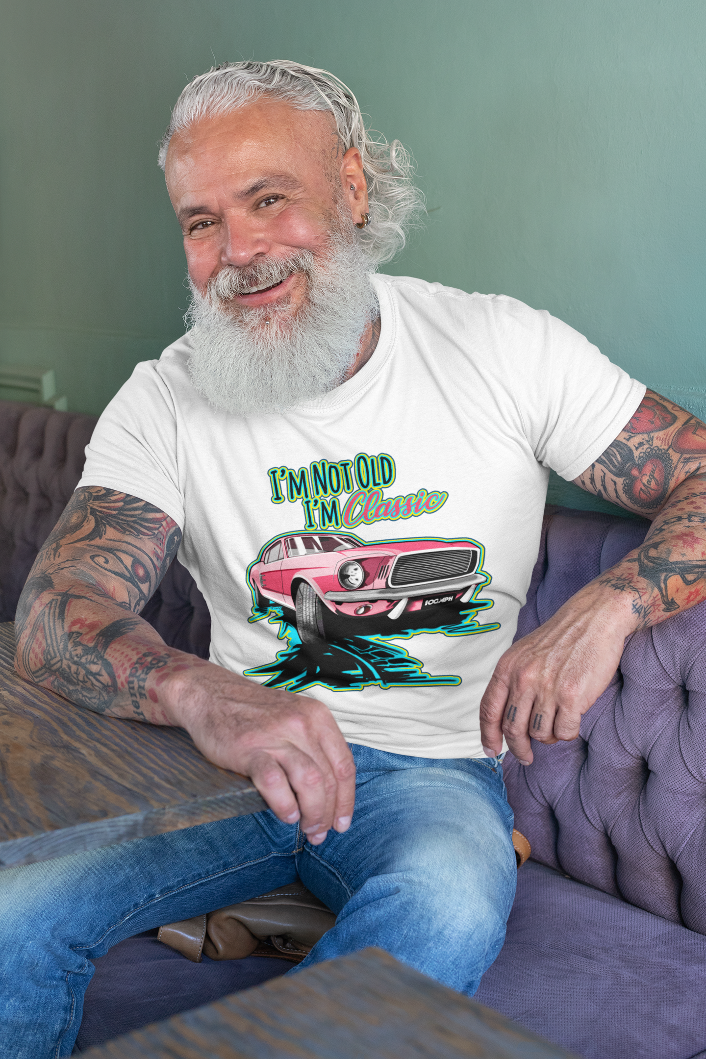 Image of A man sitting at a table, wearing a tee shirt with an image of a Ford Mustang, and text reading 