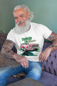 A man sitting at a table, wearing a tee shirt with an image of a Ford Mustang, and text reading "I'm not old, I'm Classic"