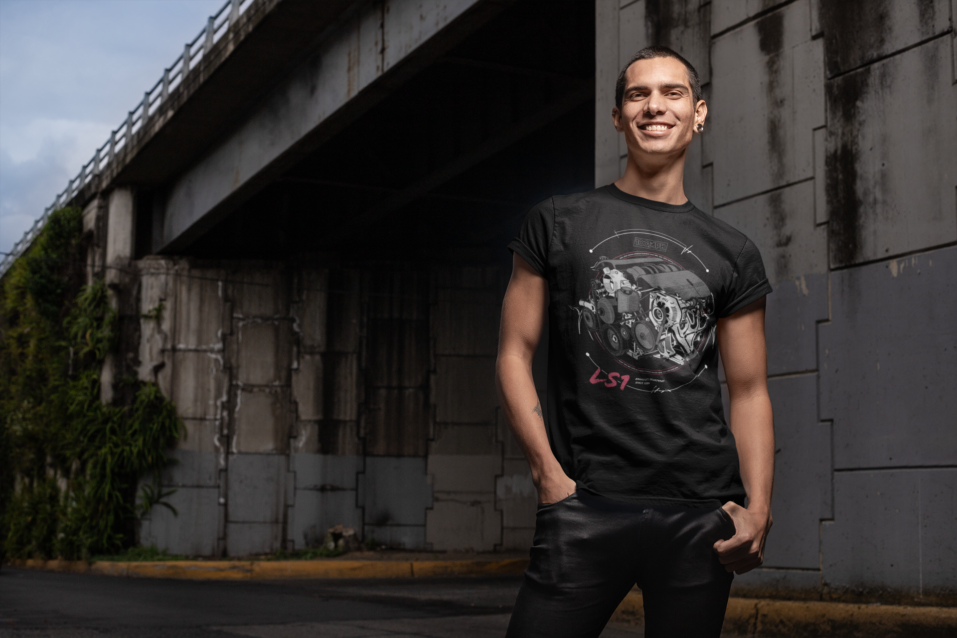 Image of A man by a bridge, wearing a tee-shirt with a Chevy LS1 engine printed on the front. Made by 100mph