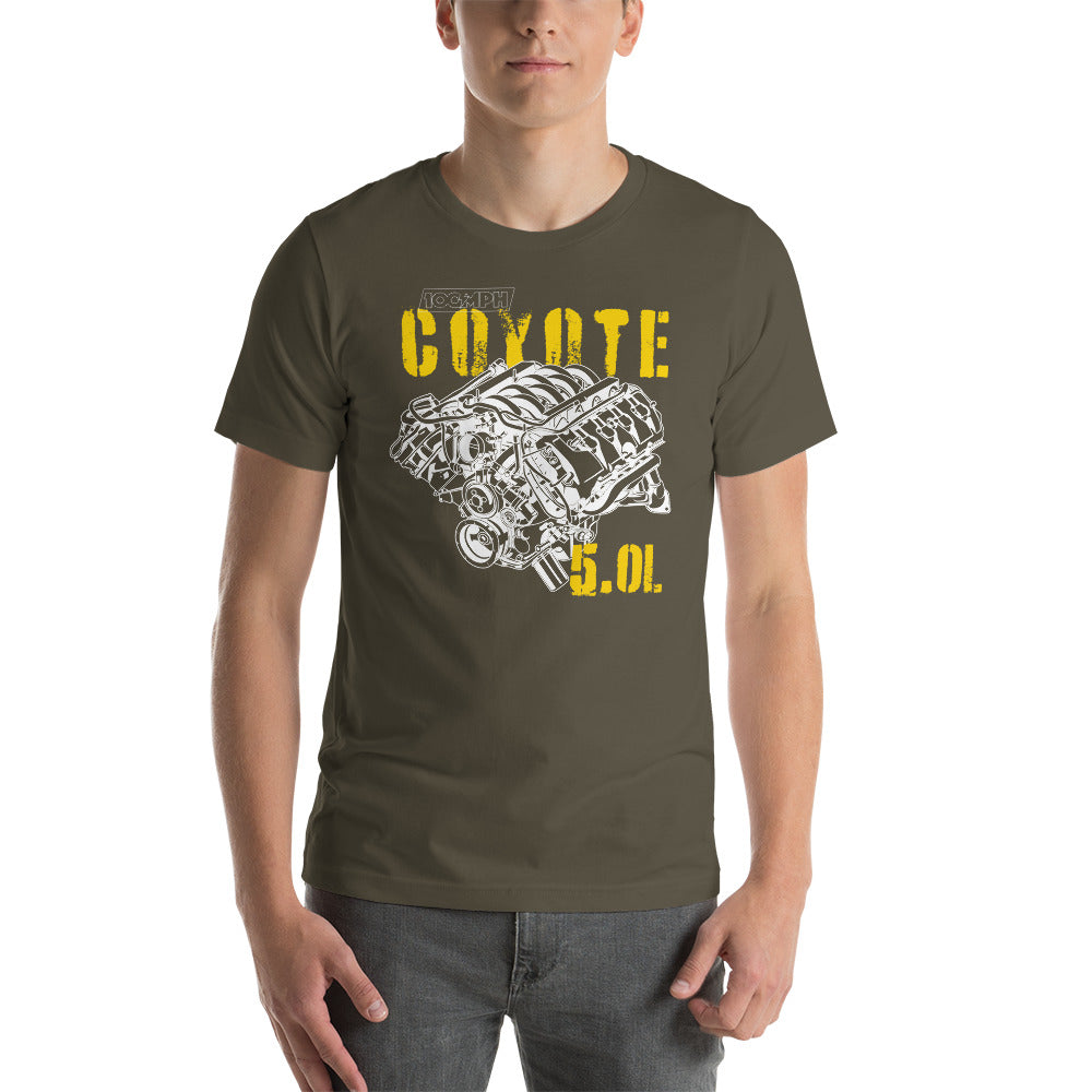 A man standing. He's wearing an army green tee shirt with an image of a Coyote engine. The tee shirt has text that reads "Coyote 5.0L". 