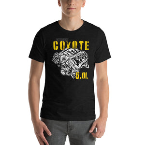 A man standing. He's wearing a black tee shirt with an image of a Coyote engine. The tee shirt has text that reads "Coyote 5.0L". 