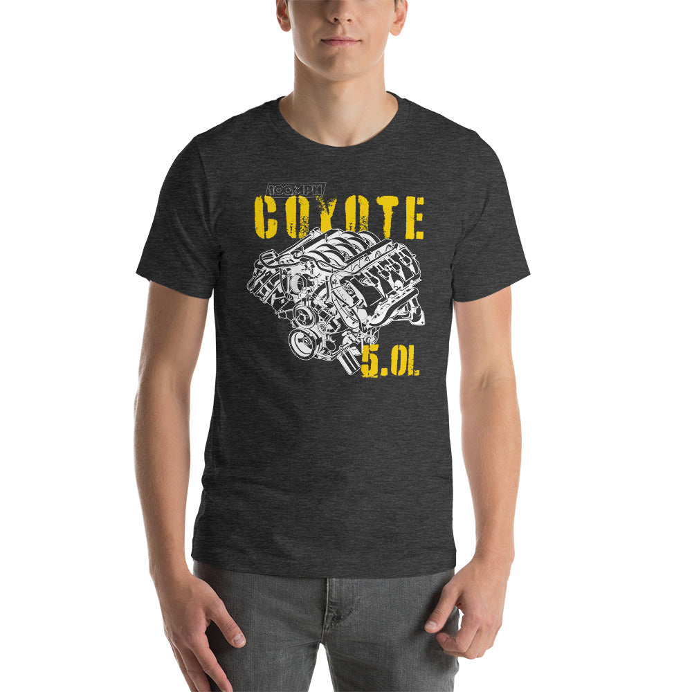A man standing. He's wearing a dark grey tee shirt with an image of a Coyote engine. The tee shirt has text that reads "Coyote 5.0L". 